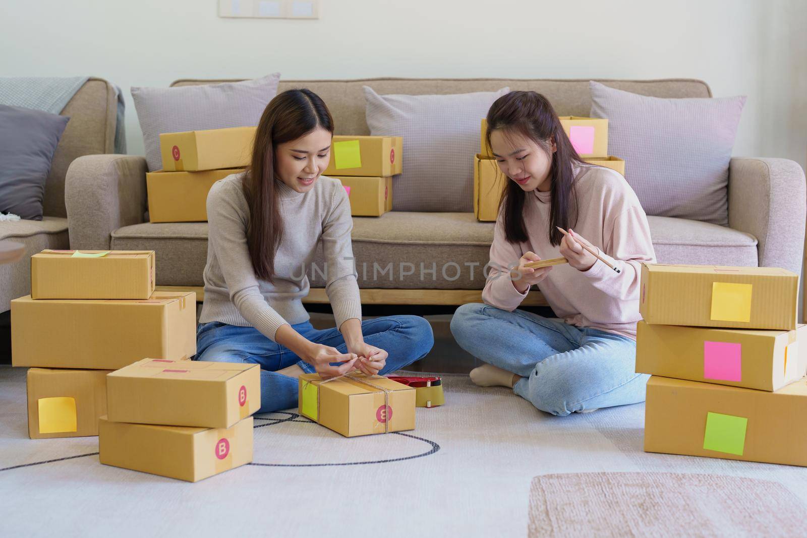 Portrait of Starting small businesses, two Asian woman check online orders Selling products working with boxs freelance work at home office, sme business concepts