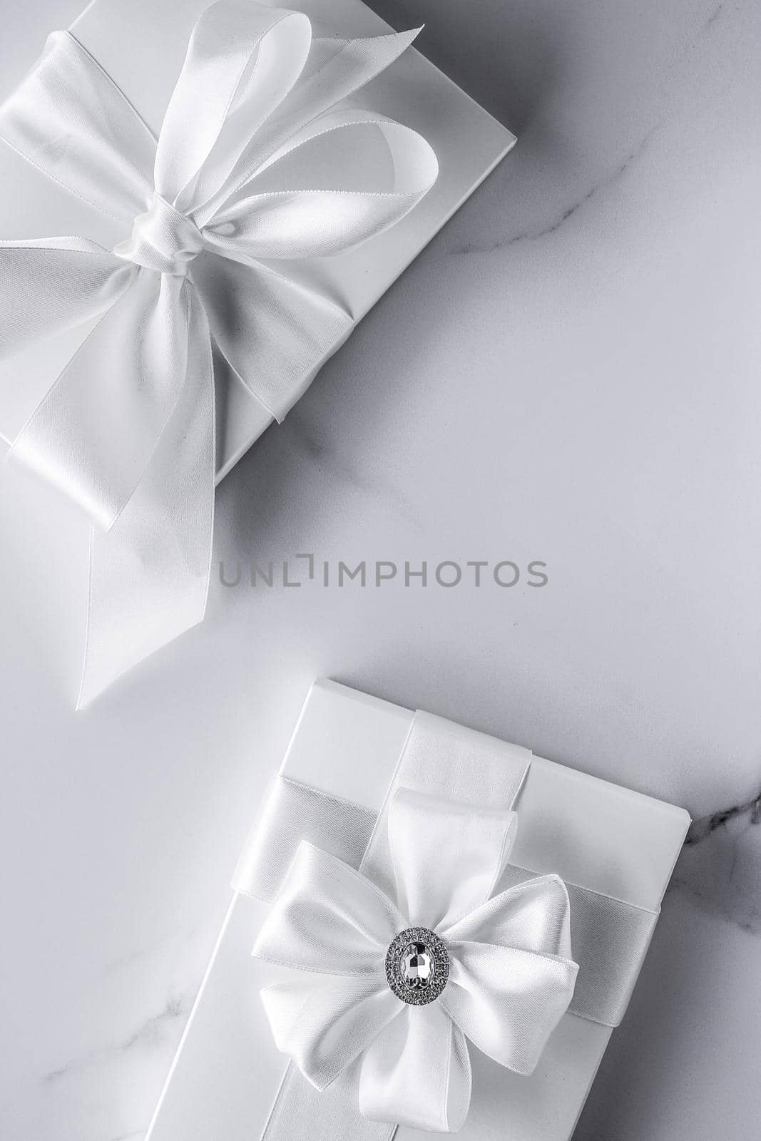 Luxury wedding gifts with silk bow and ribbons on marble background by Anneleven