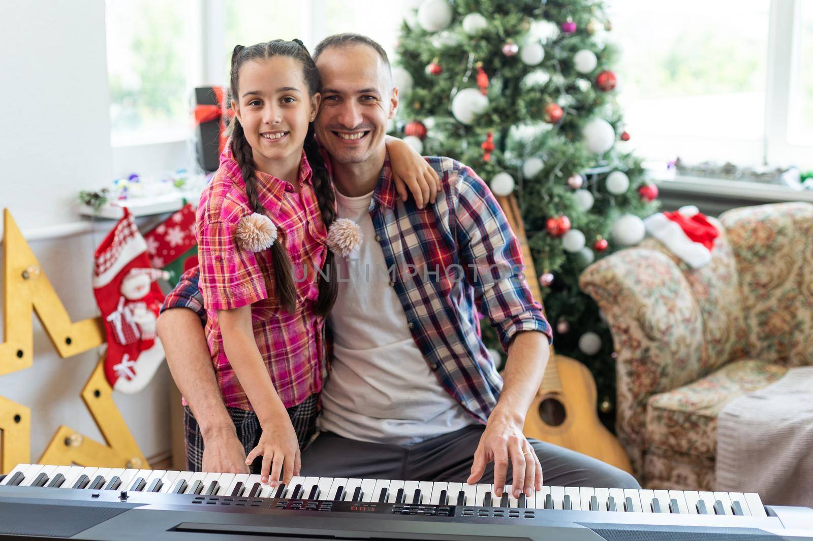 father and daughter at the piano with Christmas decor.