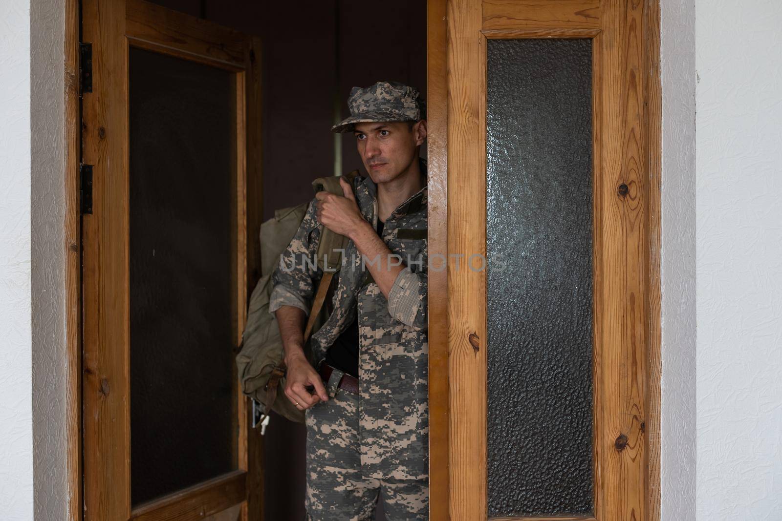 White military man wearing uniform with backpack at home.