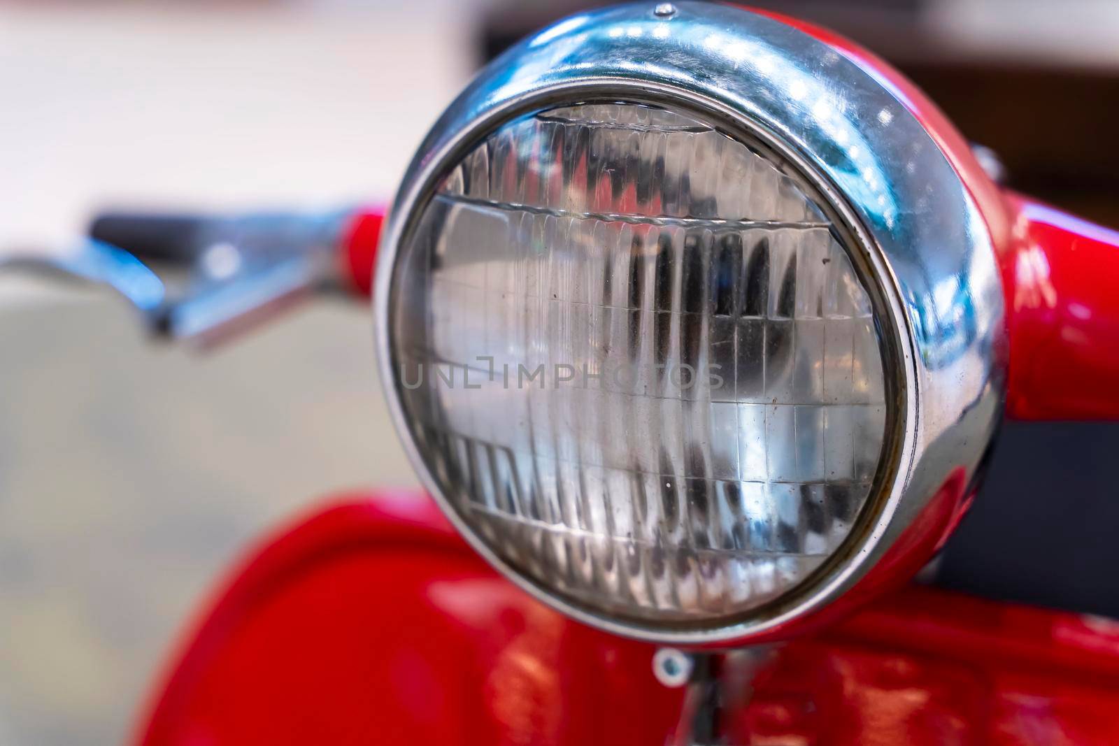 headlight, handlebar and control levers of a vintage red scooter. by audiznam2609