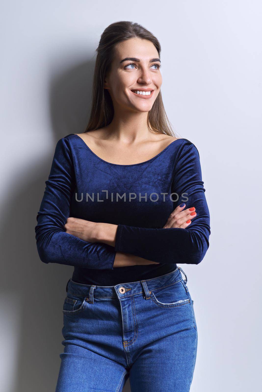 Beauty fashion portrait of young woman in blue body, jeans, white background. Successful beautiful confident smiling woman with healthy white teeth, straight healthy hair