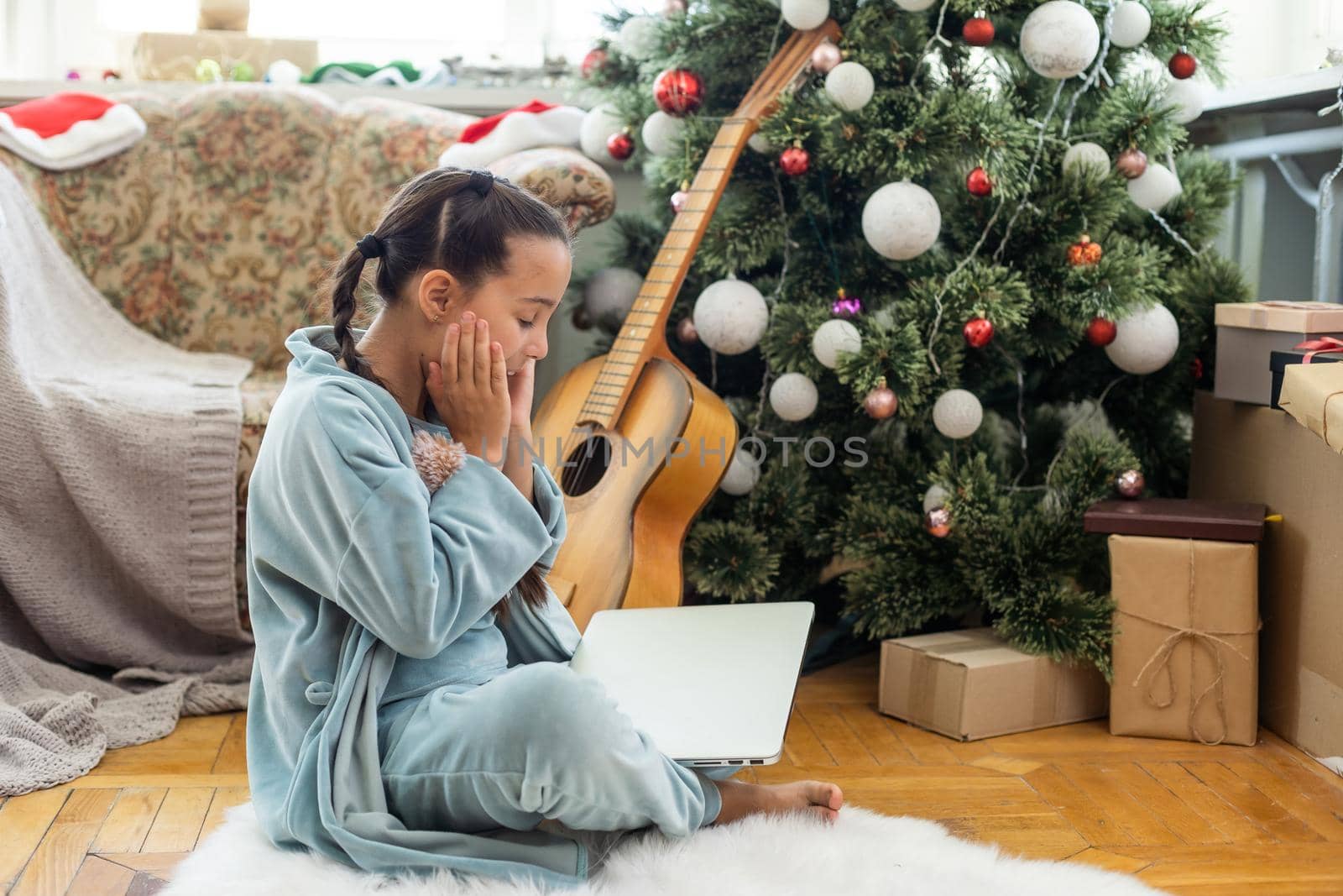 little girl sitting, looking at a laptop with a smile before Christmas by Andelov13