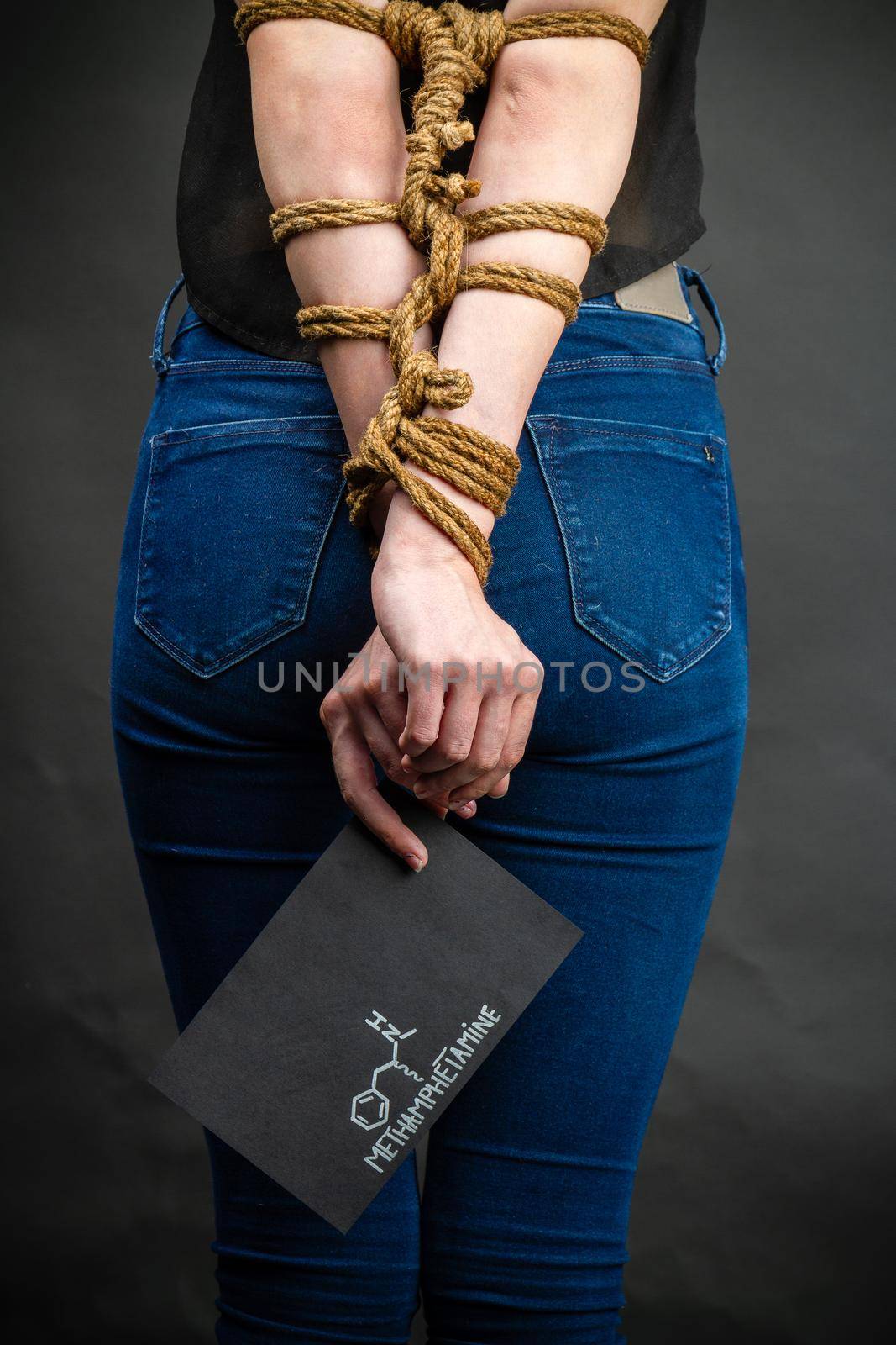 Vertical shot of bound girl holds paper with methamphetamine molecule. by super_picture