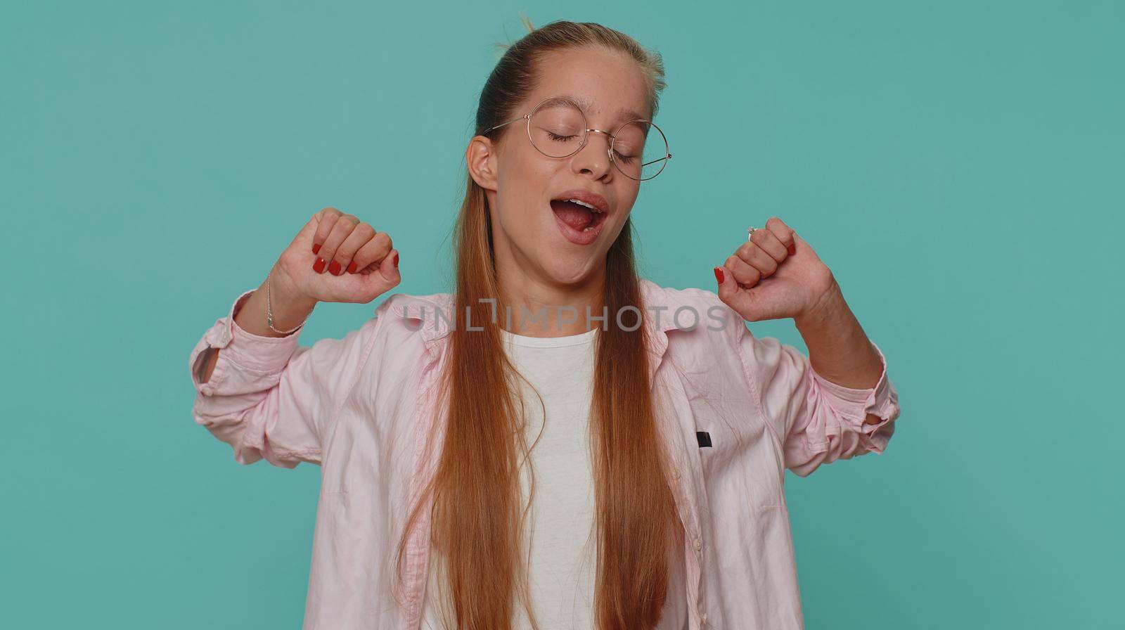 Tired overworked teenager young girl yawning, sleepy inattentive feeling somnolent lazy bored gaping suffering from lack of sleep. Bored student child kid isolated on blue studio background indoors