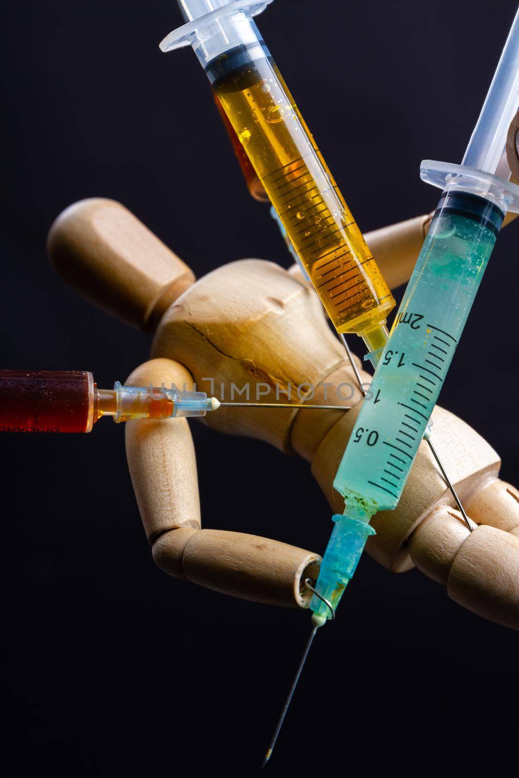 Close-up wooden doll dummy mannequin with stucked syringes. Drug trap concept.