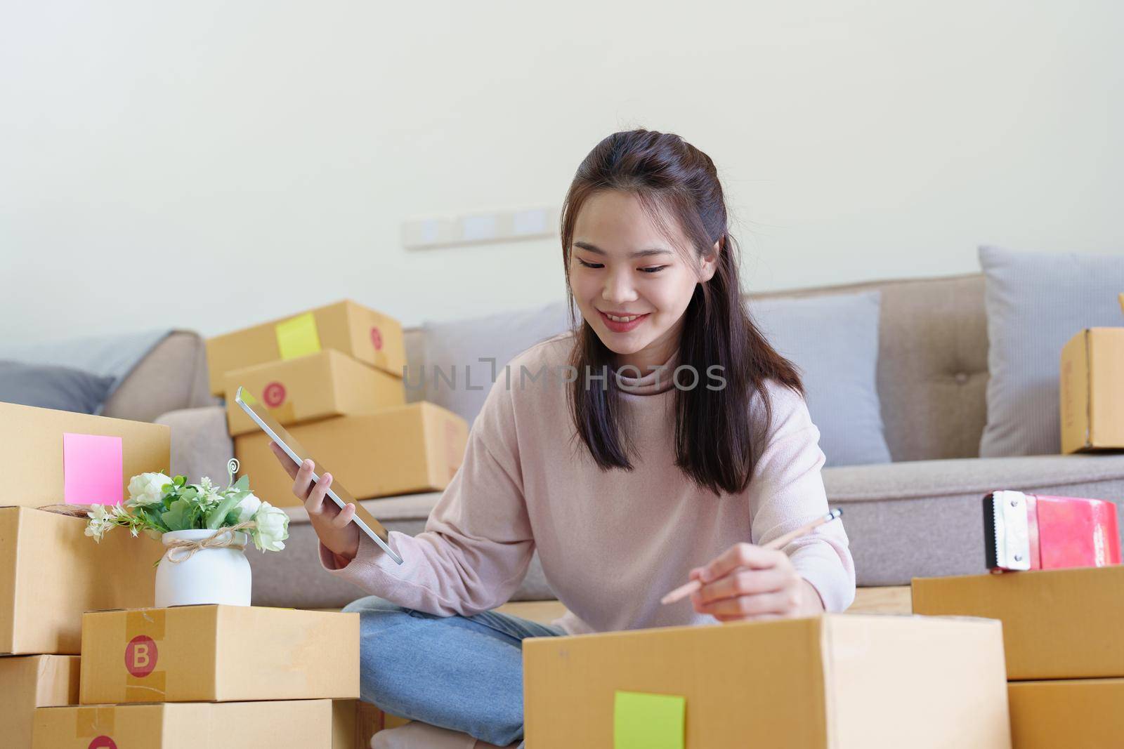 Portrait of Starting small businesses, Asian woman check online orders Selling products working with boxs freelance work at home office, sme business concepts