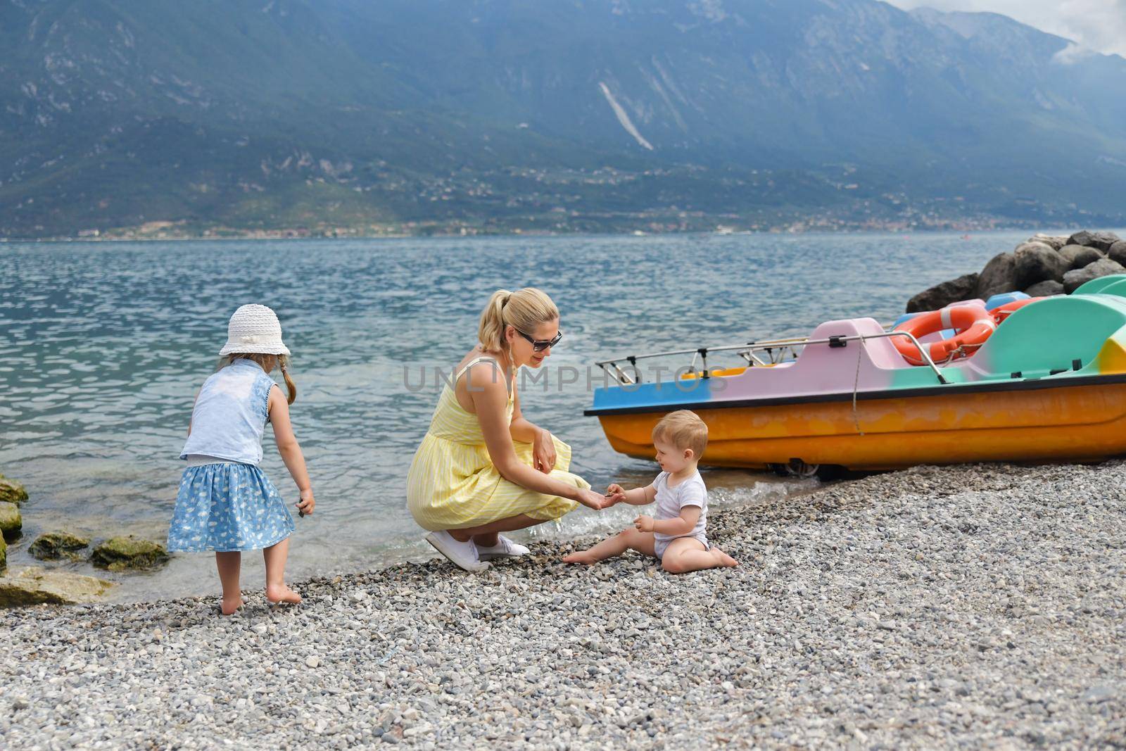 Young mother with children resting on the shore of a Garda Lake