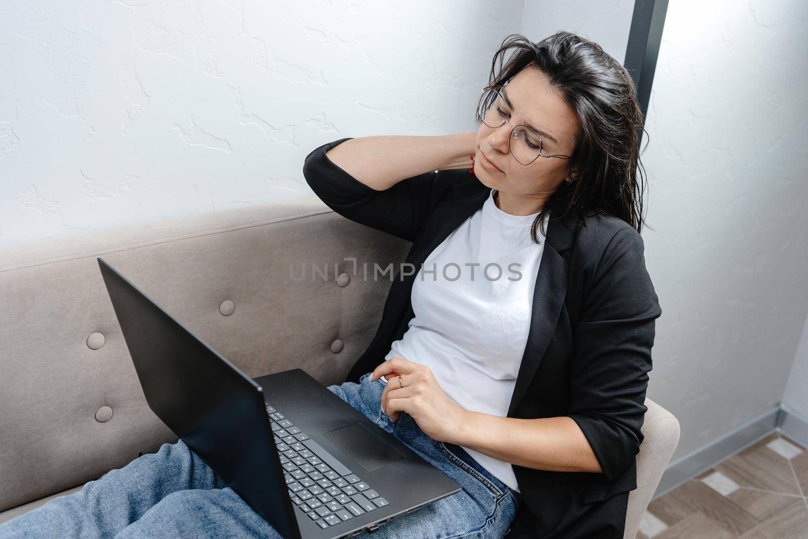 A young and beautiful businesswoman, tired of work. A girl working at her laptop at home rubbing her tired neck.