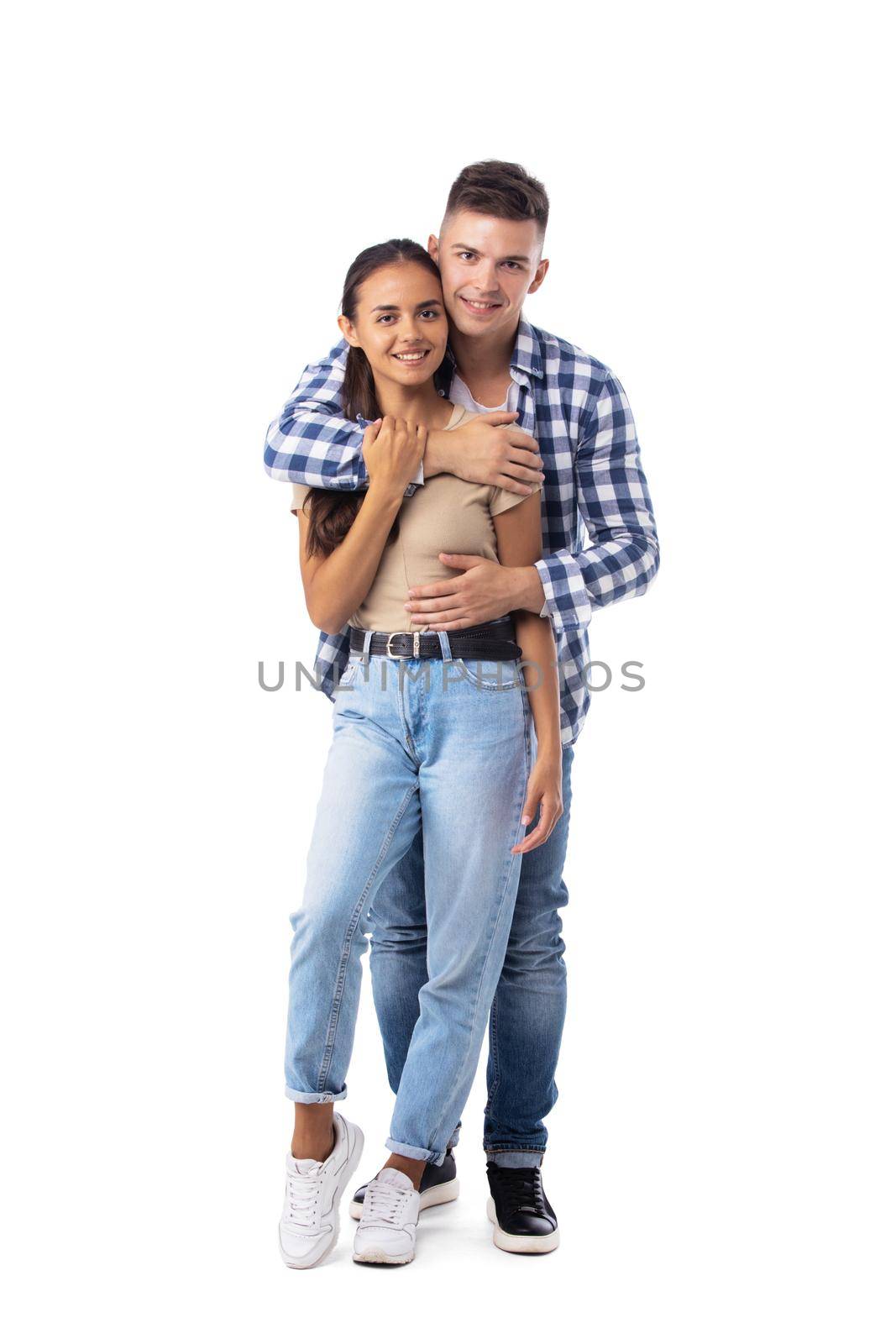 Smiling young couple embracing and standing full length isolated on white background