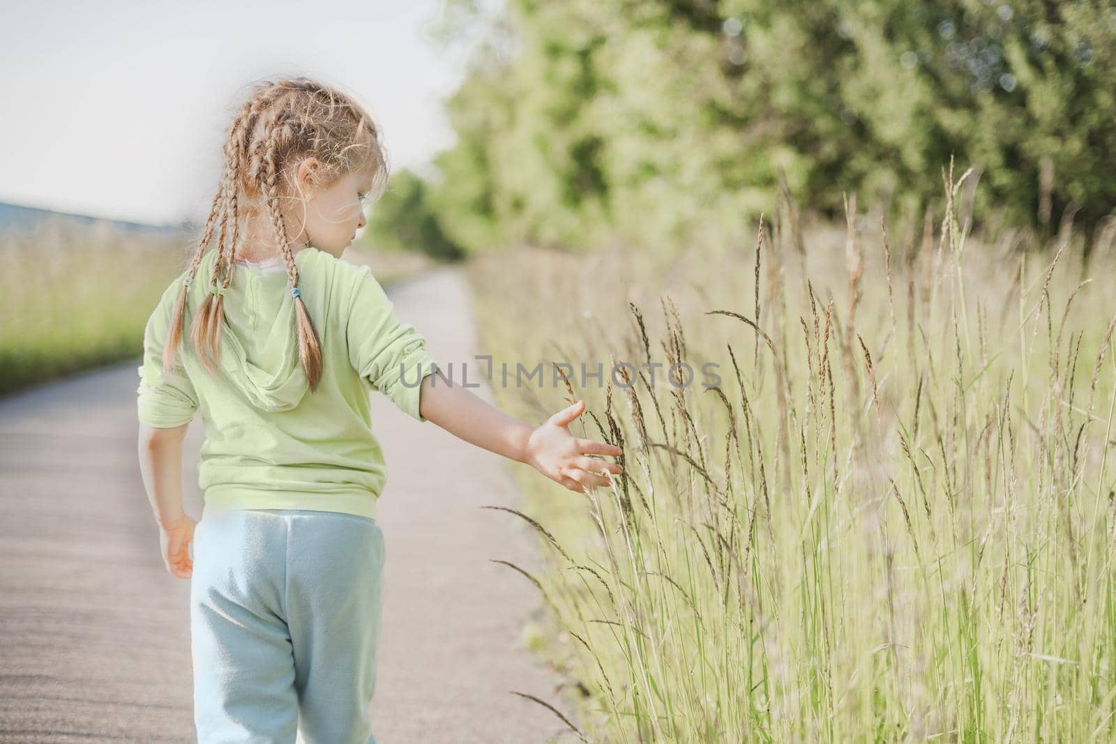 Girl with pigtails touching green grass