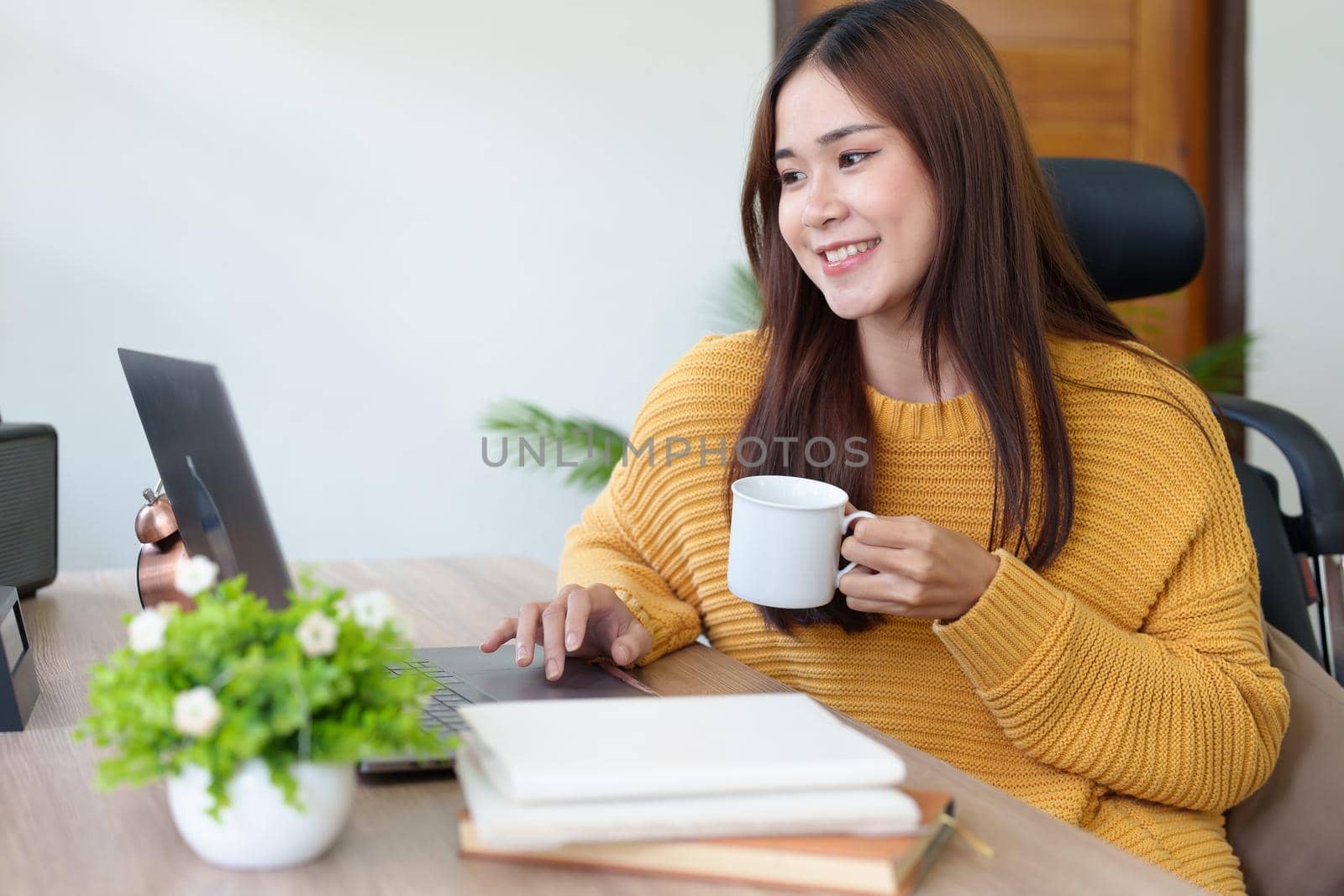 Portrait of an Asian businesswoman or business owner taking a coffee break while working in the office.