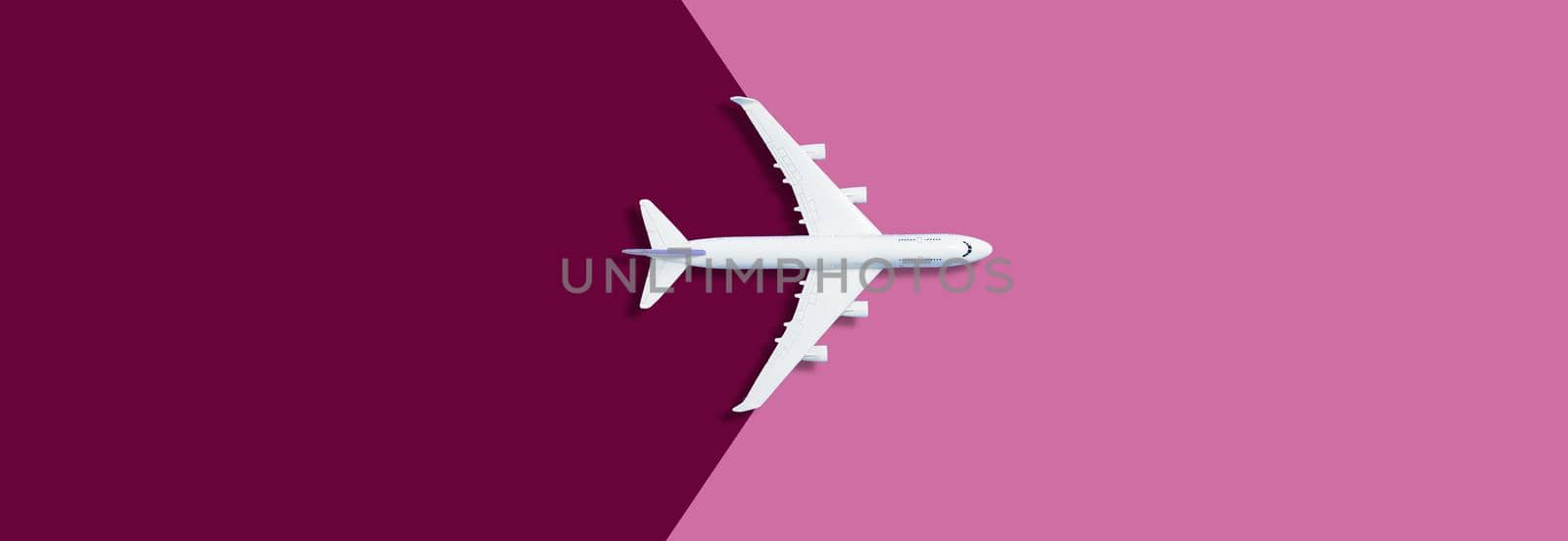 Flat lay of miniature toy airplane on purple background. High quality photo