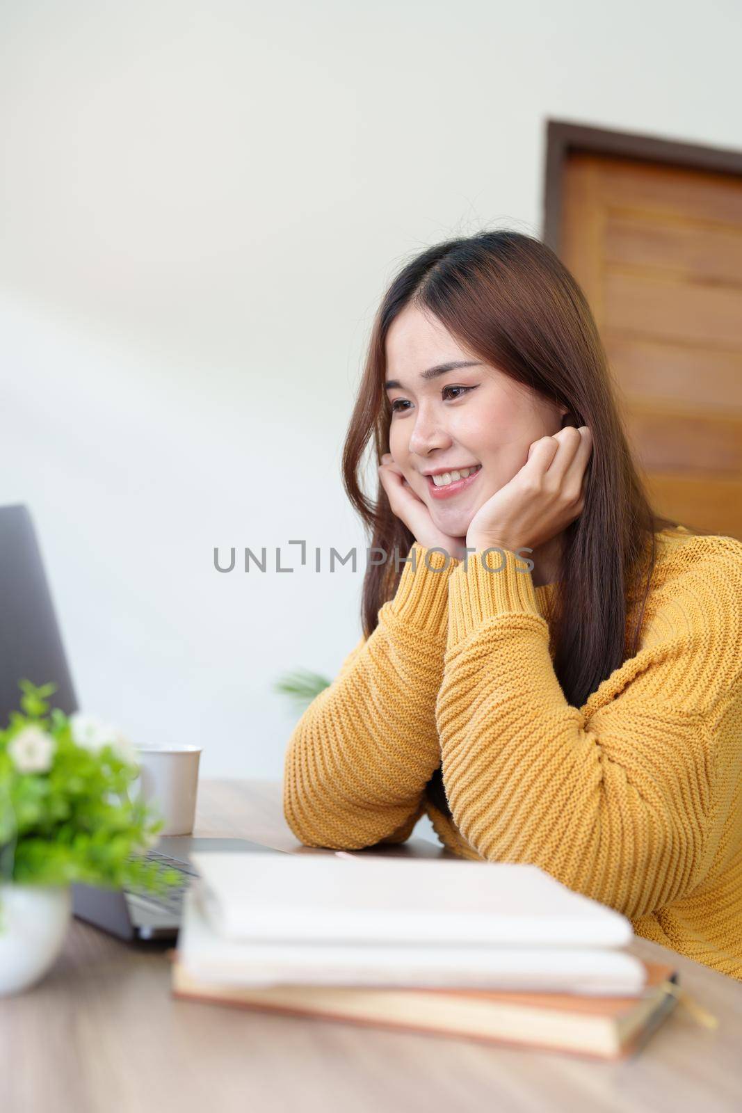 woman smiling happily while using computer at home by Manastrong