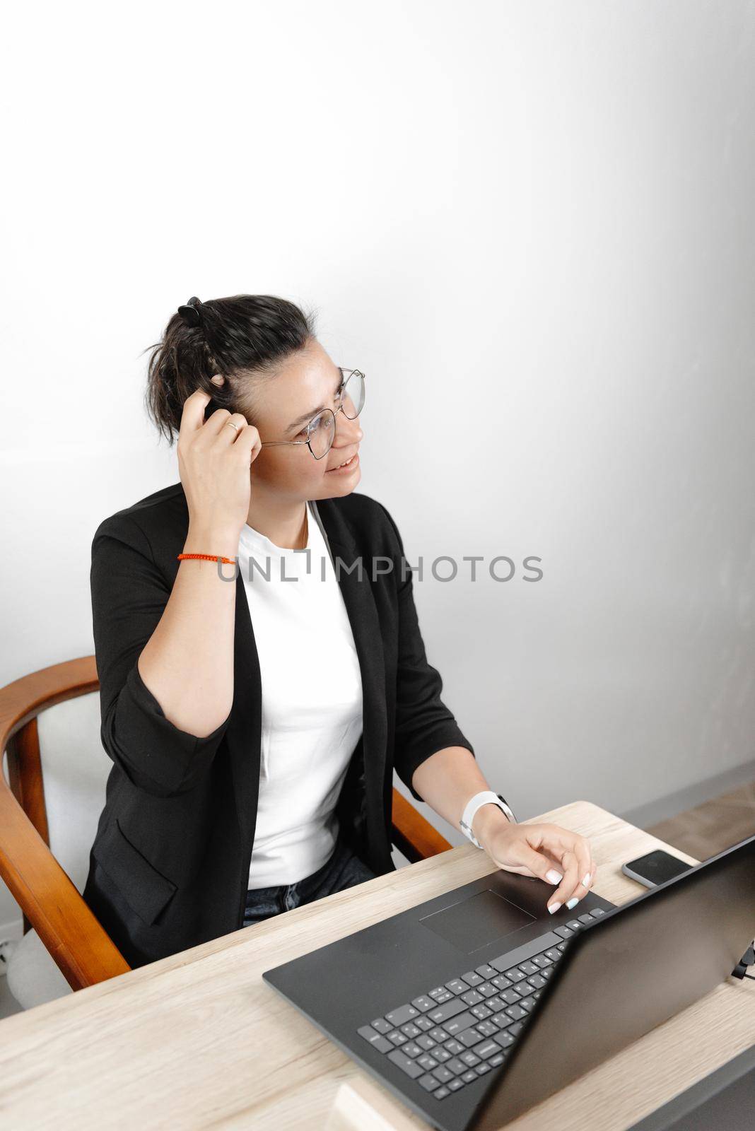 Serious thoughtful young businesswoman economist pondering in the office, wearing a jacket and T-shirt and glasses.