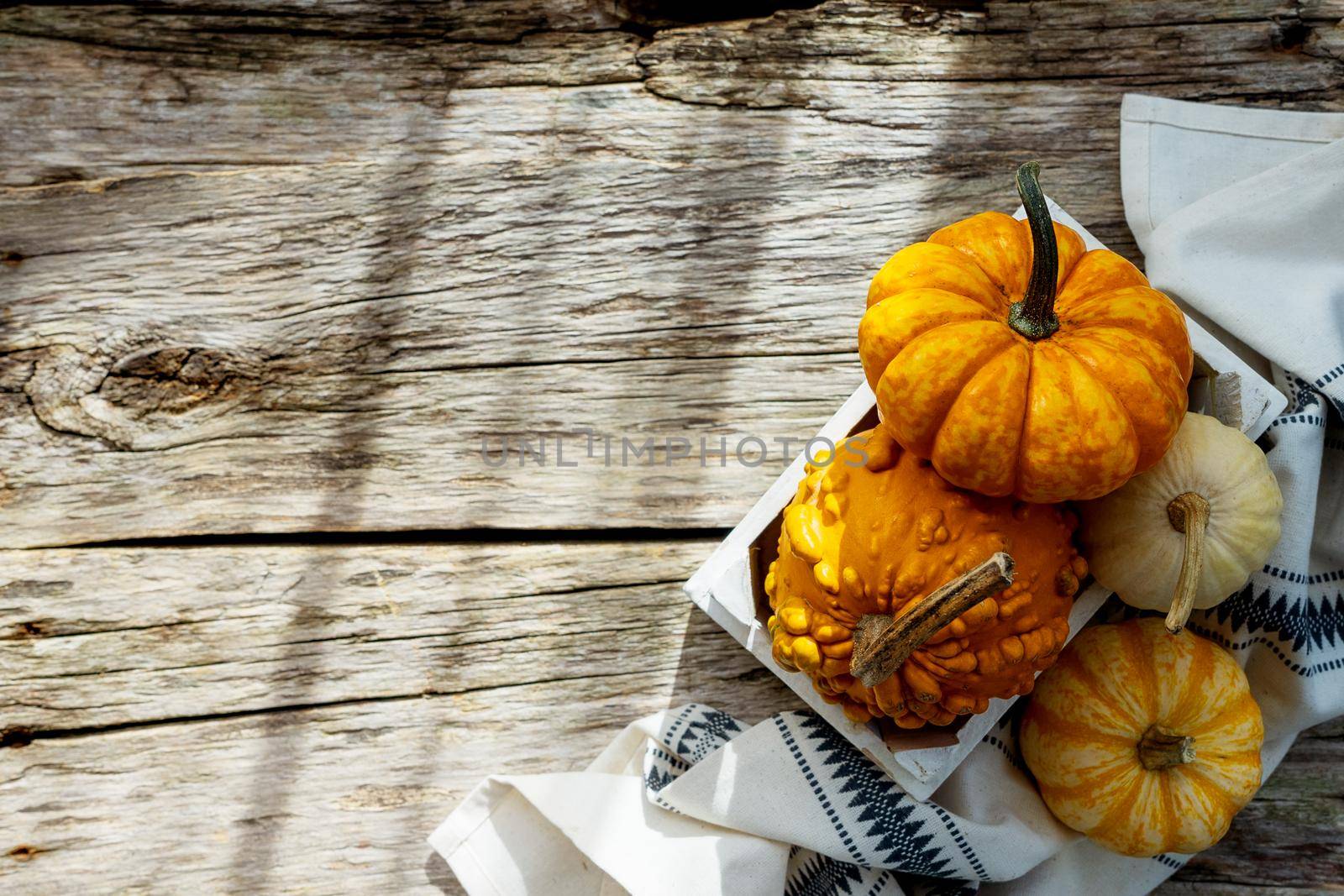 Pumpkins on a rustic napkin, on a wooden background, close-up, top view by Ramanouskaya