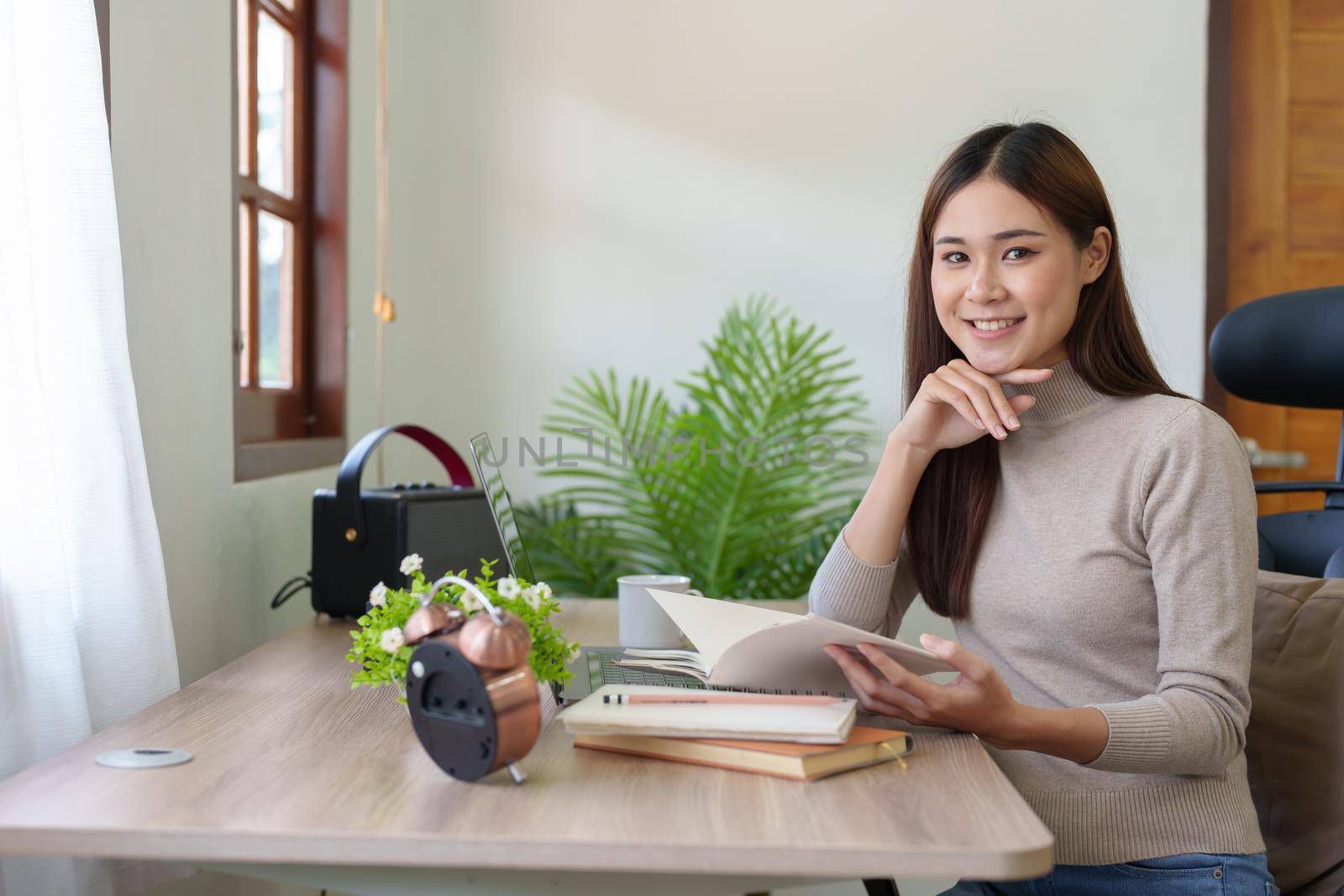 woman sitting at home reading a notebook and using a computer by Manastrong