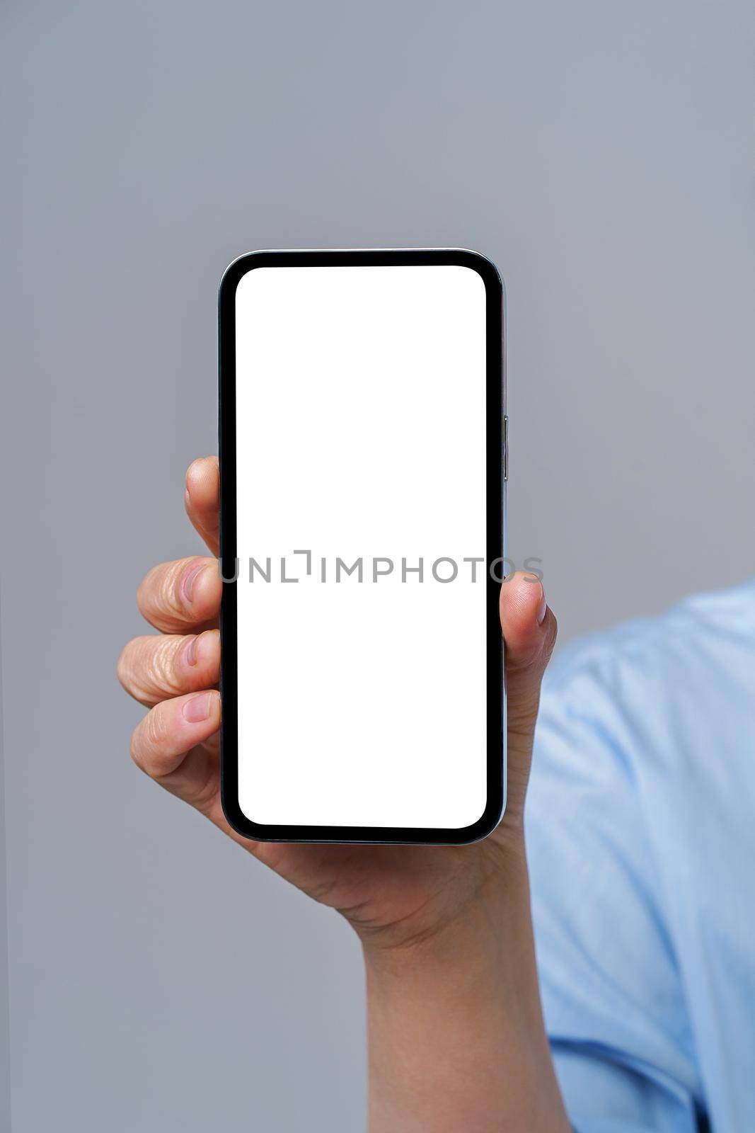 Mature woman hand holding smartphone with white screen isolated on white background. Modern phone with touch screen in woman hand. Close up. Mock up mobile app advertising.