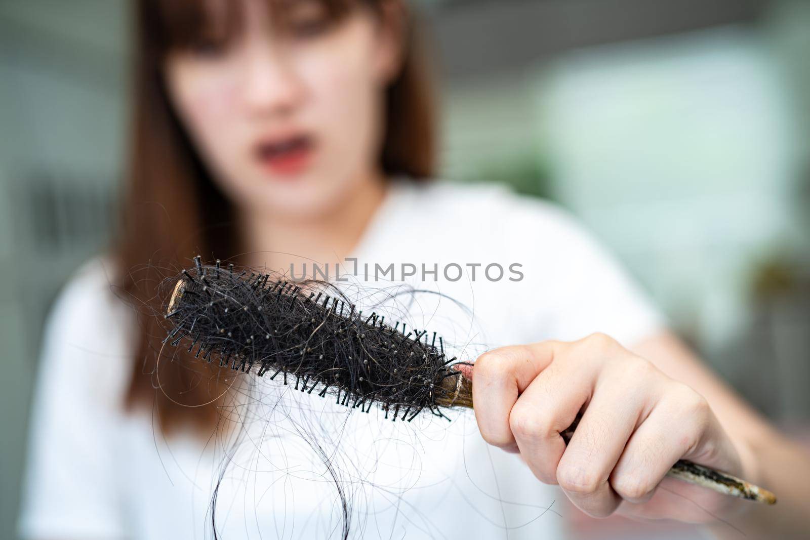 Asian woman have problem with long hair loss attach to comb brush.