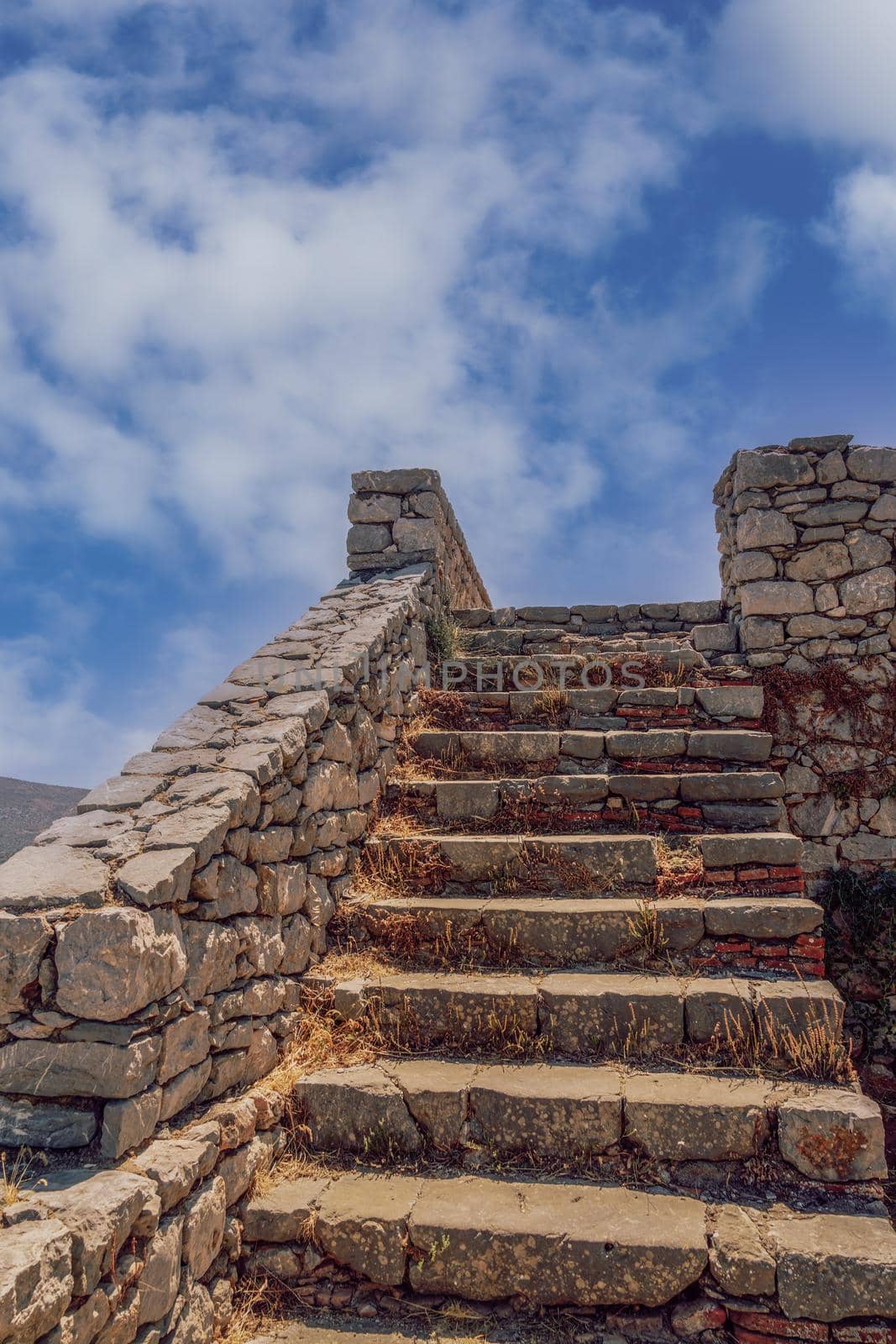 Day view of empty stone old staircase steps without people, against blue sky with clouds.