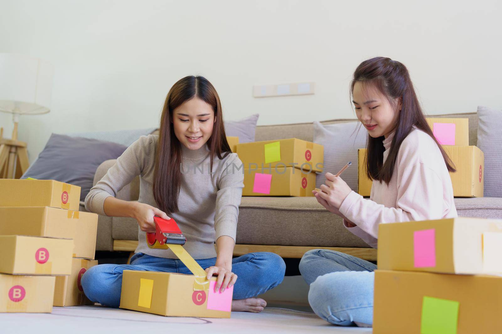 Portrait of Starting small businesses, two Asian woman check online orders Selling products working with boxs freelance work at home office, sme business concepts