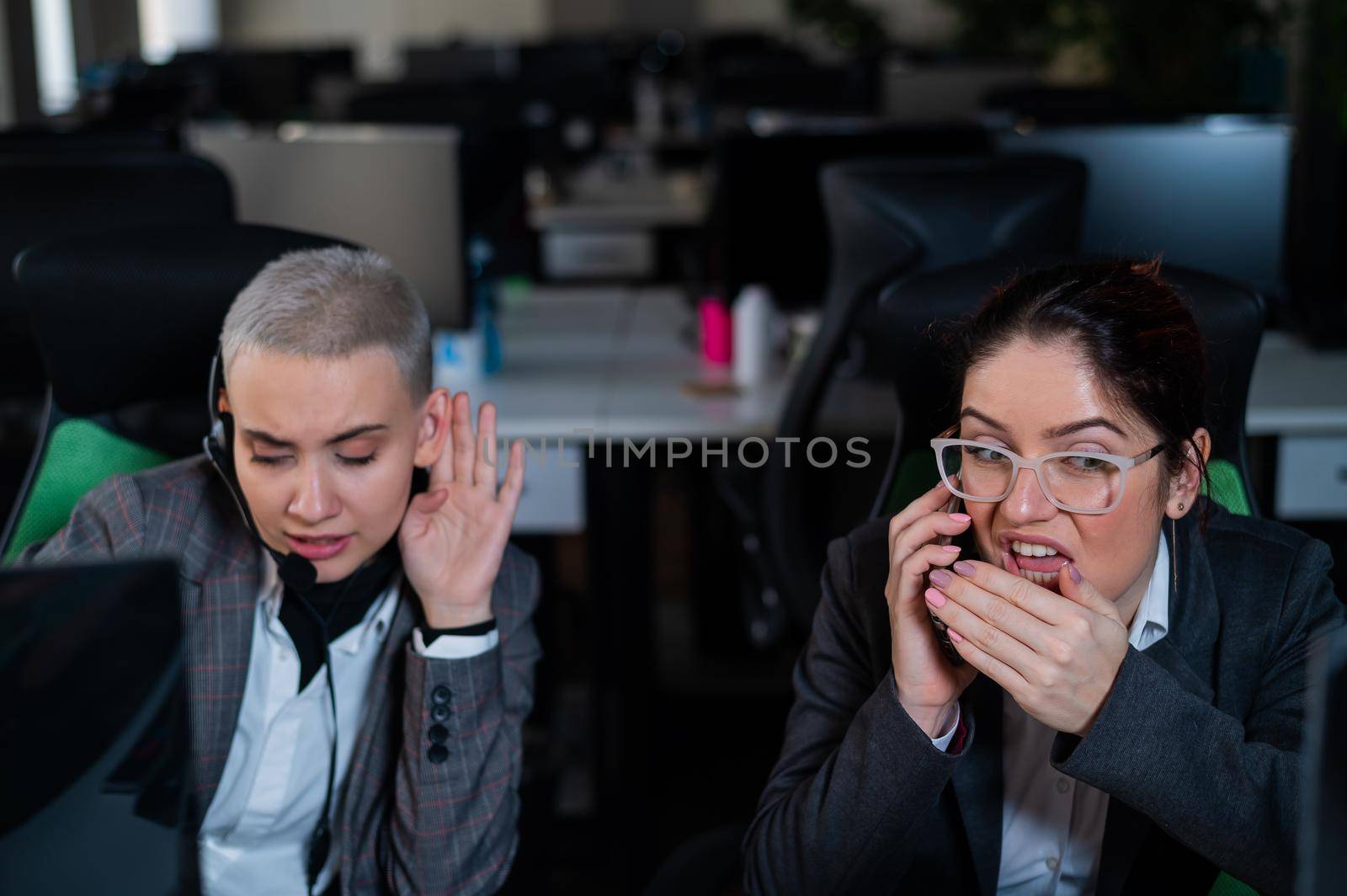 Curious young woman overhears a private telephone conversation of a colleague in the office.
