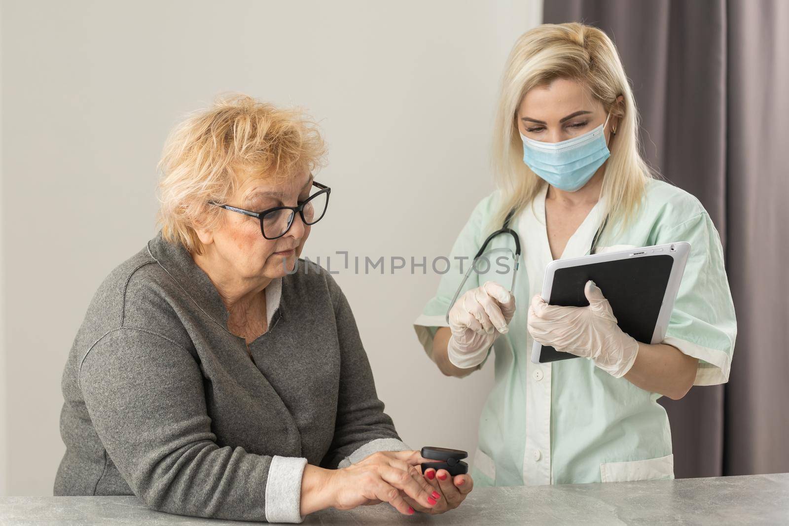 Hand of senior woman with an attached pulse oximeter on fingertip,old elderly measuring heart rate, checking oxygen saturation level in the blood, diagnosis of Coronavirus, COVID-19 at home, health care.