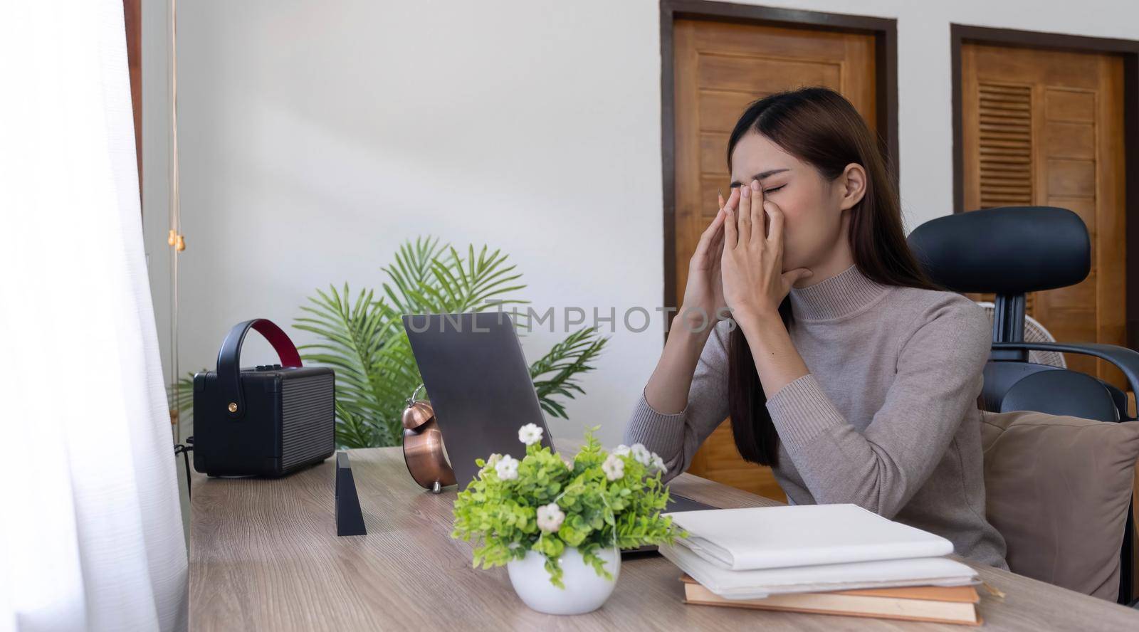 Asian young woman seriously working on computer laptop in house. She thinking find solution problem of work by wichayada