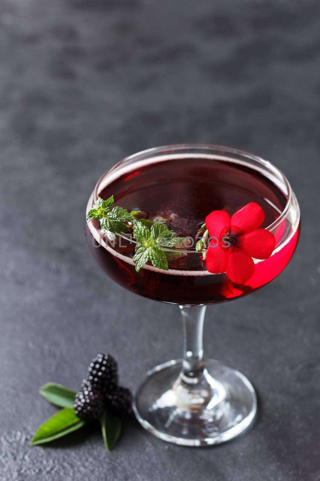 Refreshing lemonade with blackberries, ice and mint on a black background. Copy space,vertical photo