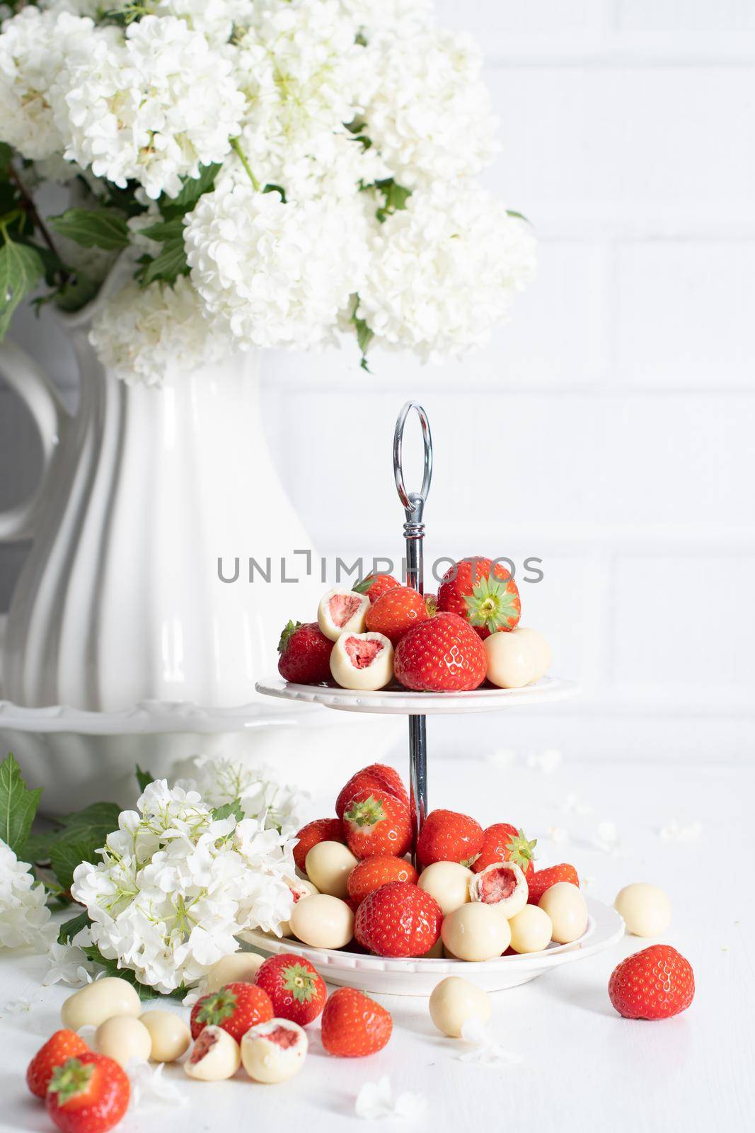 vase with white chocolate covered strawberries and fresh strawberries against porcelain vase with hydrangea, vintage still life and summer food. High quality photo