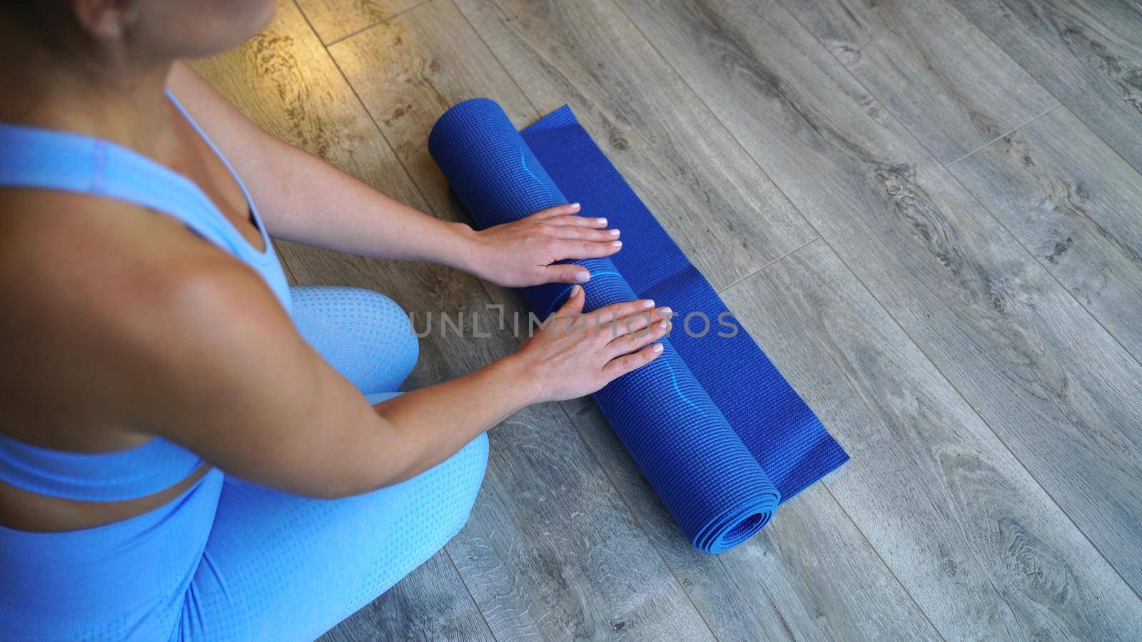 The girl twisted blue yoga mat after training