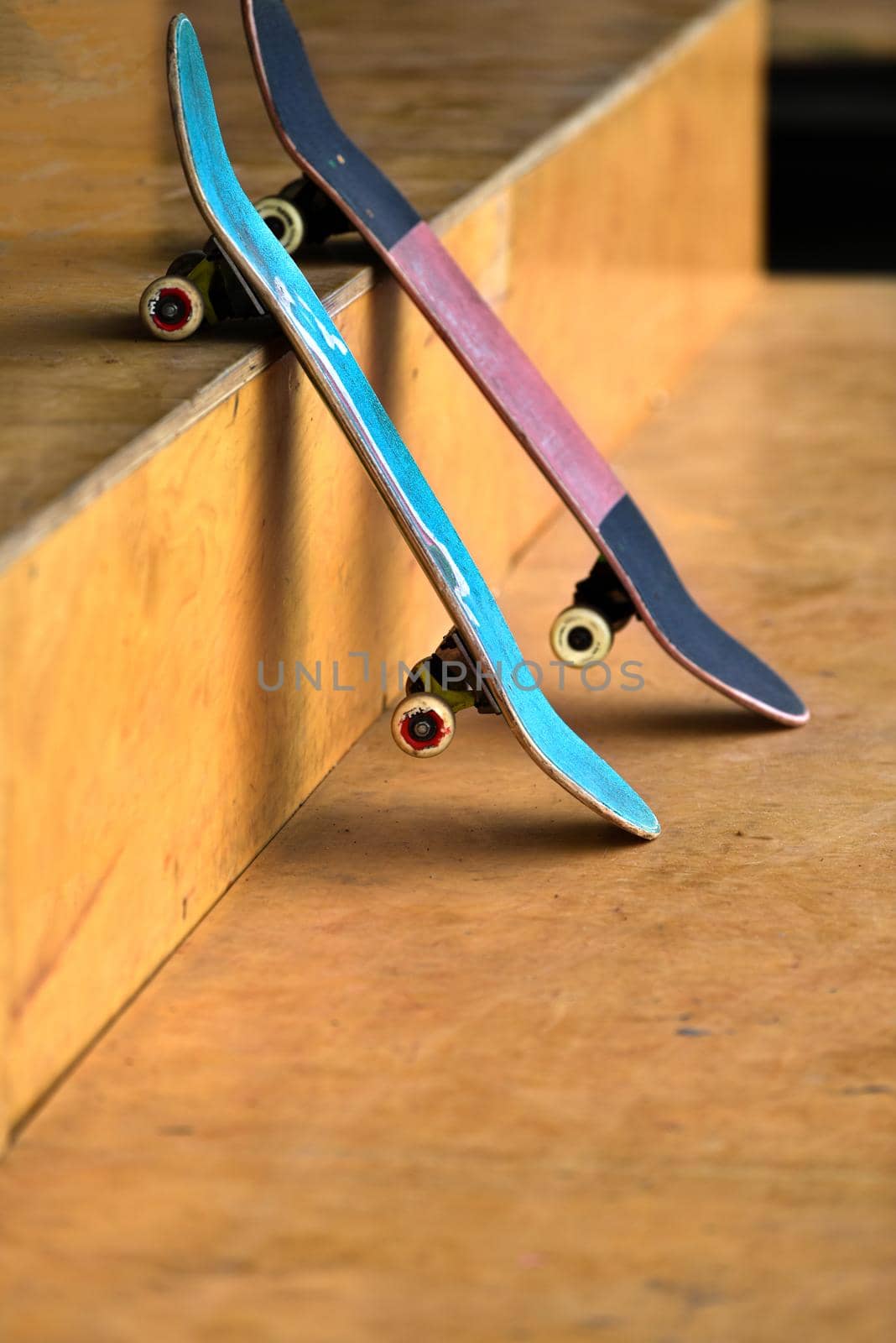Skateboards for parkour practice on flat surface of large stadium or sports activity area. two shabby skateboards are tilted. worn, old, skateboards for teens