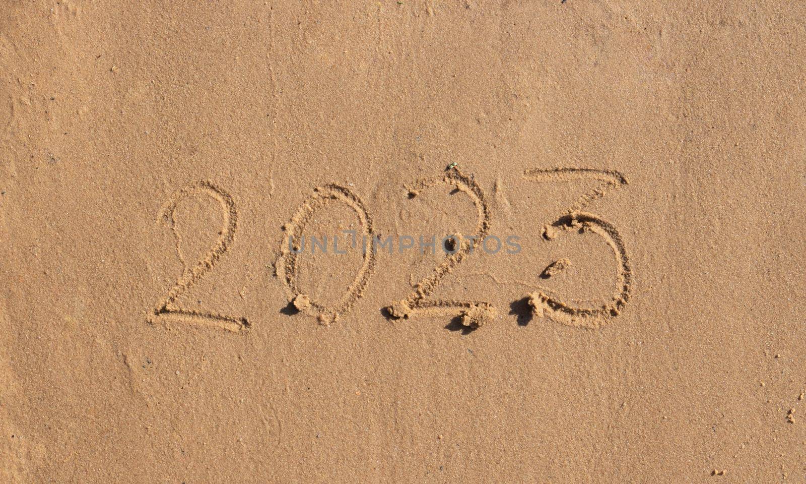 The numbers 2023 are written on the sand on the beach. The concept of the New Year. Happy New Year 2023 background. Travel during the Christmas holidays. by lapushka62