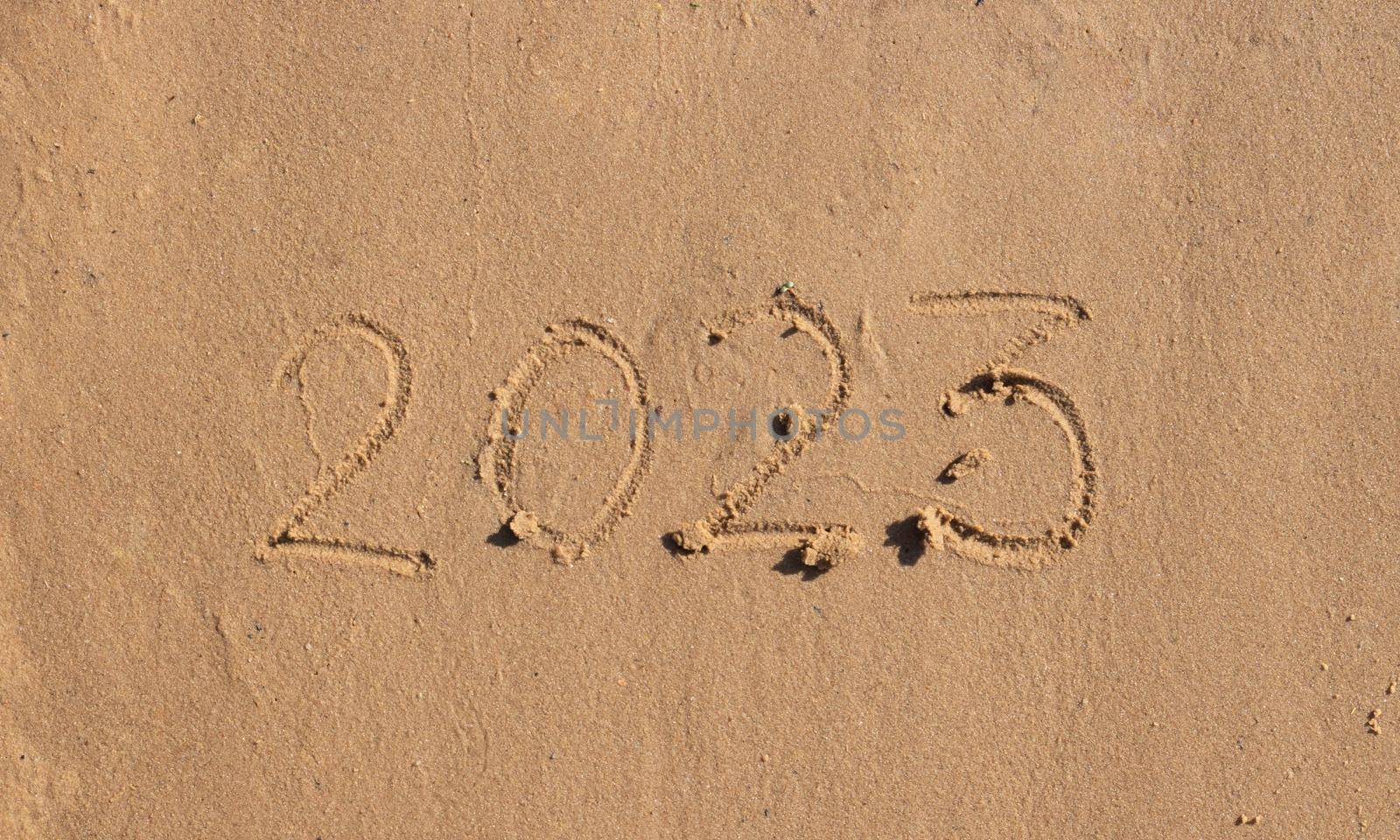 The numbers 2023 are written on the sand on the beach. The concept of the New Year. Happy New Year 2023 background. Travel during the Christmas holidays