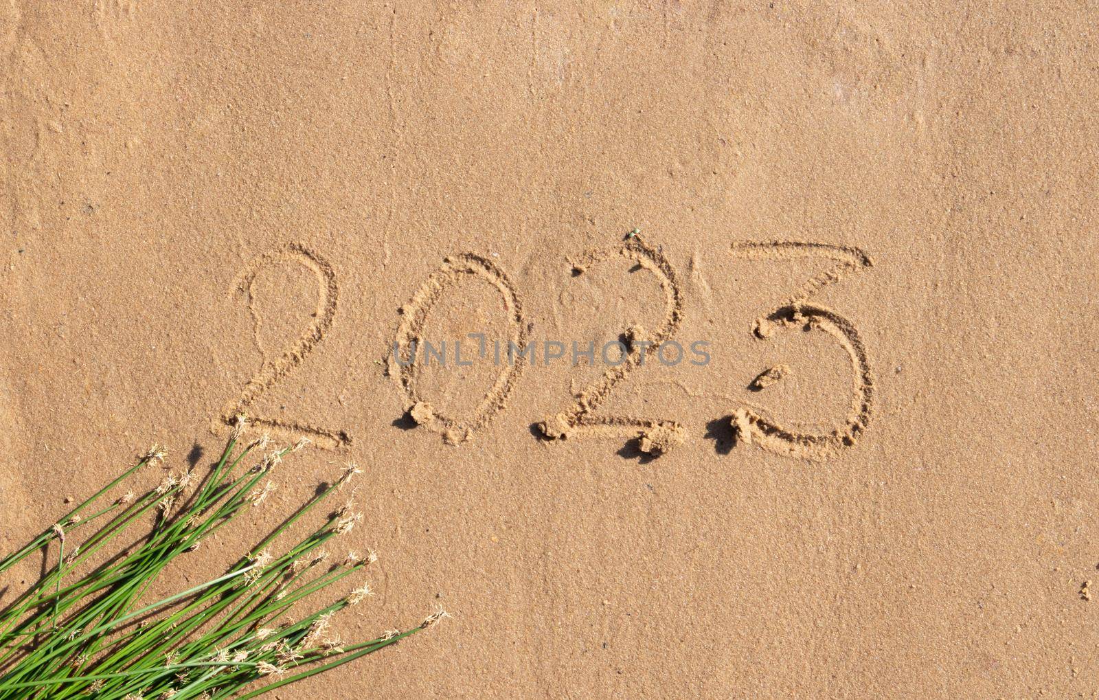 The numbers 2023 are written on the sand on the beach. The concept of the New Year. Happy New Year 2023 background. Travel during the Christmas holidays. by lapushka62