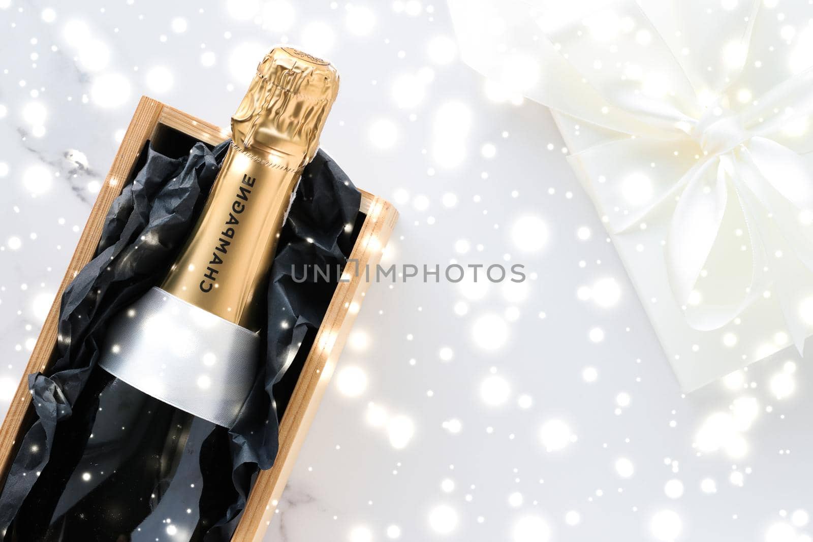 New Years Eve, happy holidays and luxury present concept - Christmas holiday champagne bottle and a gift box and shiny snow on marble background