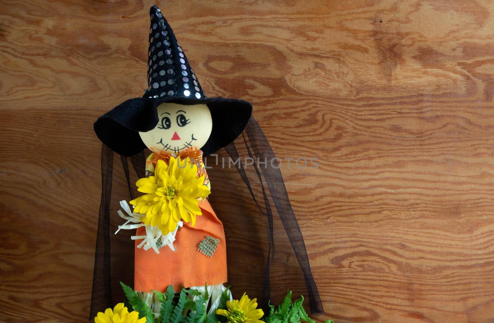 A cute little toy in a witch costume with a magic hat. Halloween. Wooden background, space for text. by lapushka62