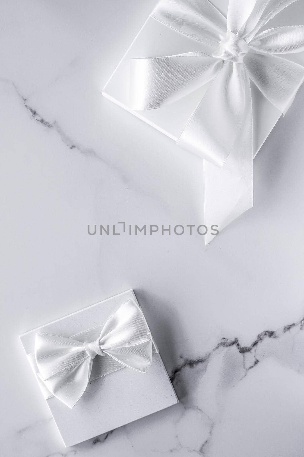 Luxury wedding gifts with silk bow and ribbons on marble background by Anneleven