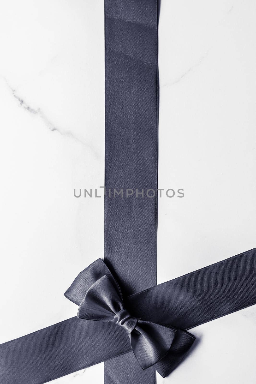 Black silk ribbon and bow on marble background, flatlay by Anneleven