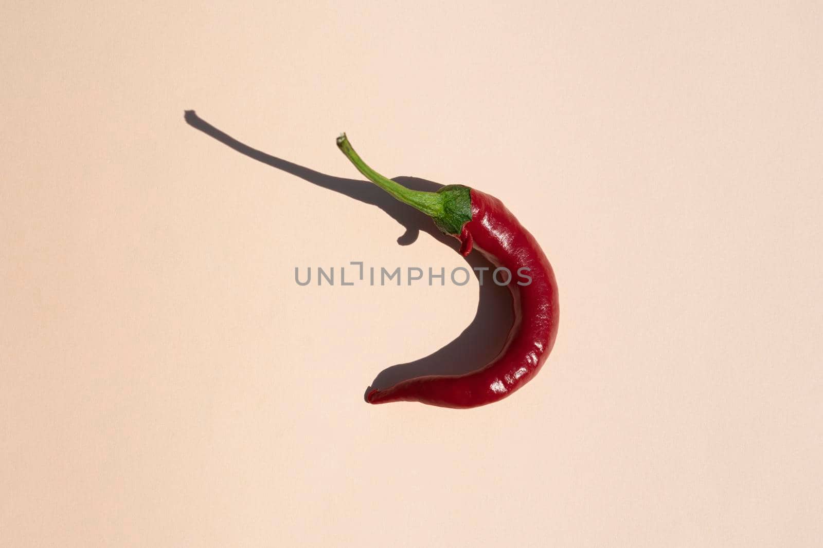 red hot pepper on a beige background with a hard shadow. High quality photo