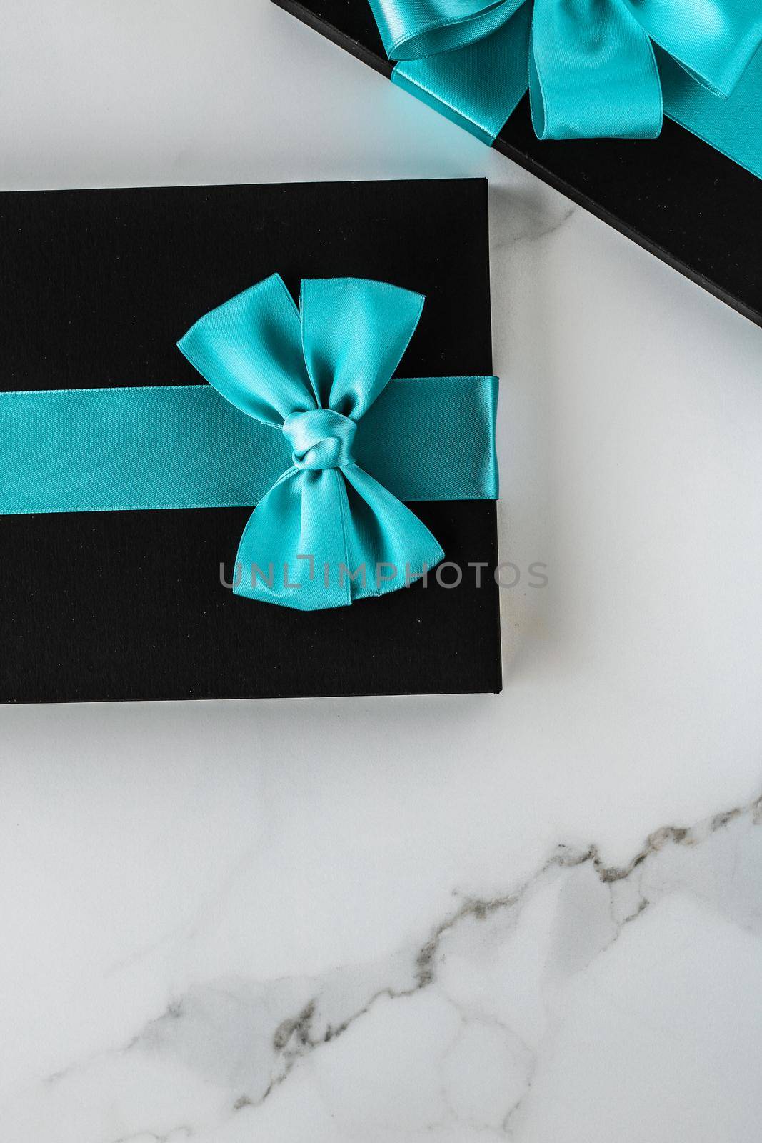 Luxury holiday gifts with emerald silk ribbon and bow on marble background by Anneleven