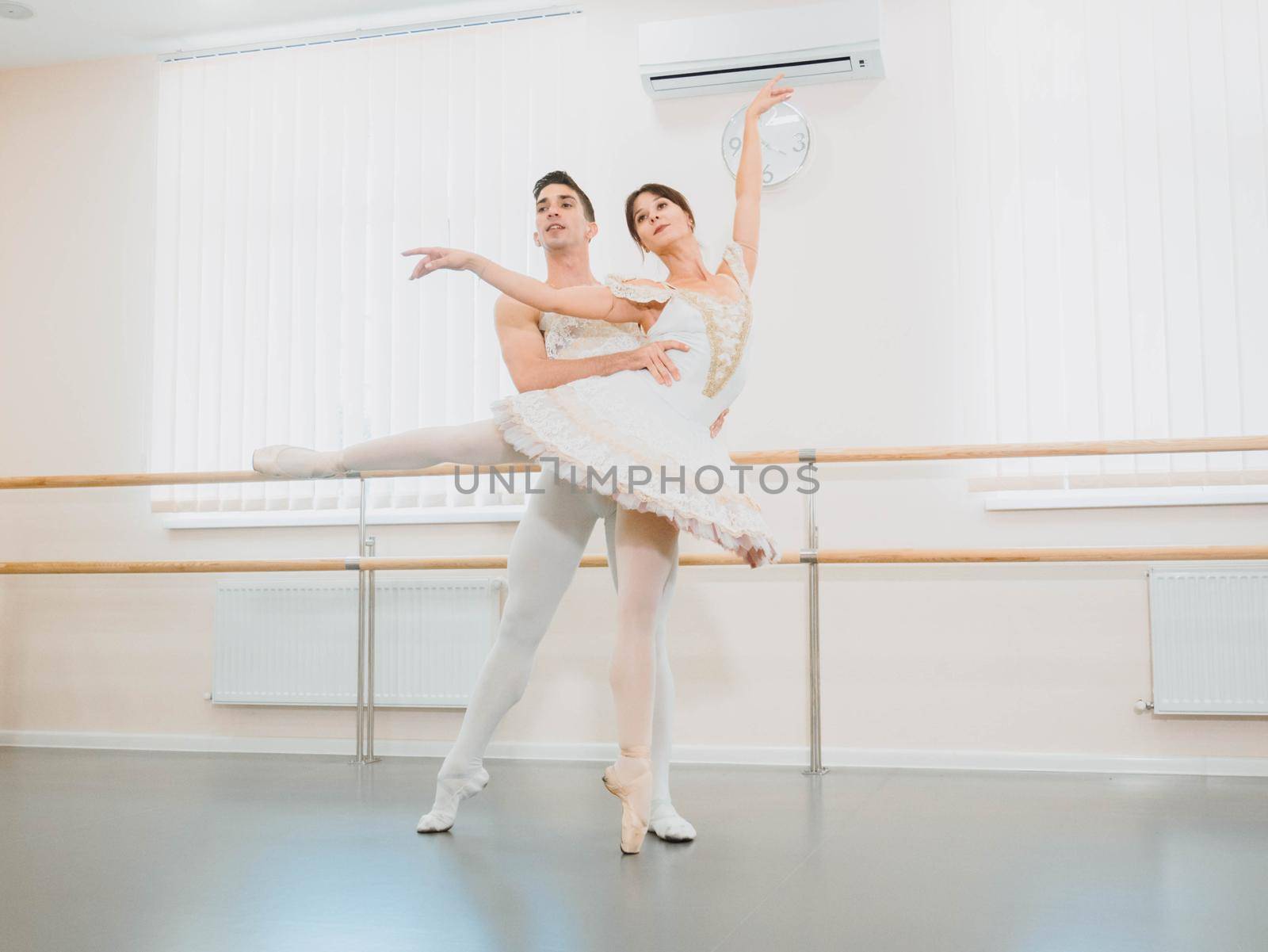 Professional, emotional ballet dancers practicing in the gym or hall with minimalism interior. Couple dancing a sensual dance before performance.