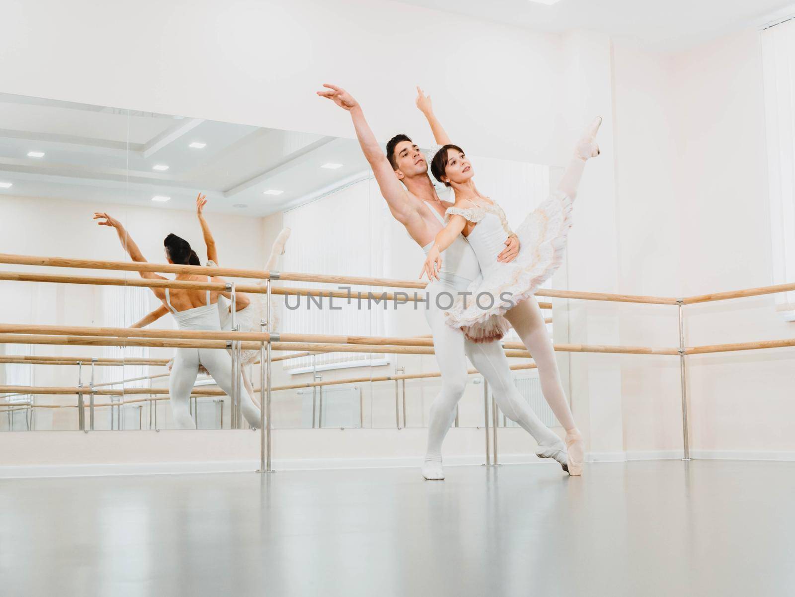 Professional, emotional ballet dancers practicing in the gym or hall with minimalism interior. Couple dancing a sensual dance before performance.