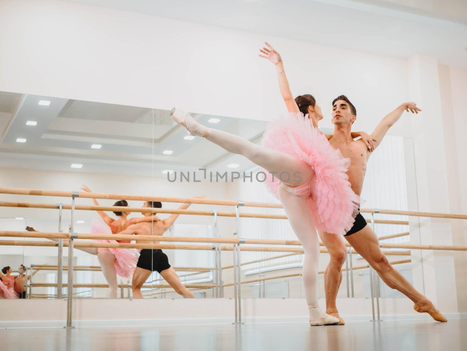 Professional, emotional ballet dancers practicing in the gym or hall with minimalism interior. Couple dancing a sensual dance before performance.