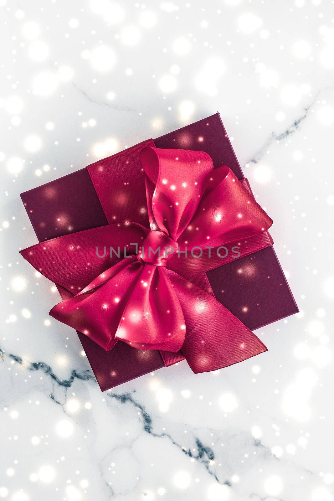 Winter holiday gifts with cherry silk bow and glowing snow on frozen marble background, Christmas presents surprise by Anneleven