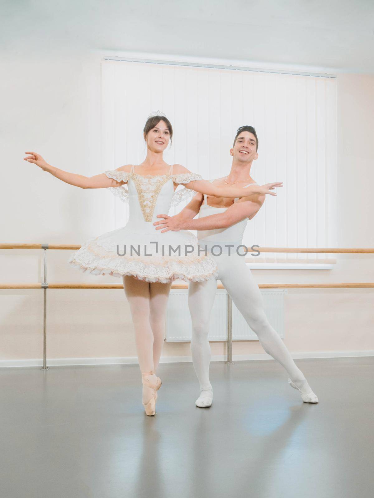 Rehearsal in the ballet hall or studio with minimalism interior. Young professional sensual couple in beautiful costumes dancing together.