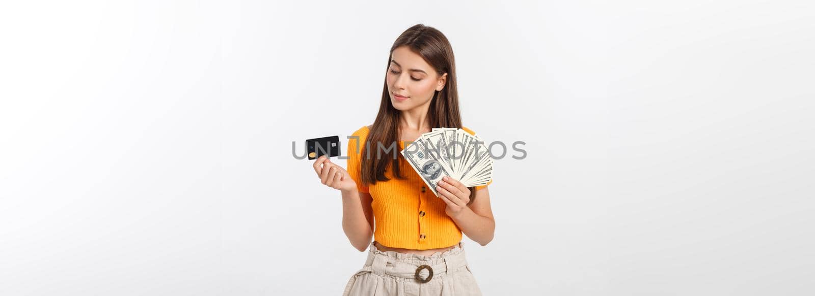 Photo of happy young woman standing isolated over grey background. Looking aside holding money and credit card by Benzoix