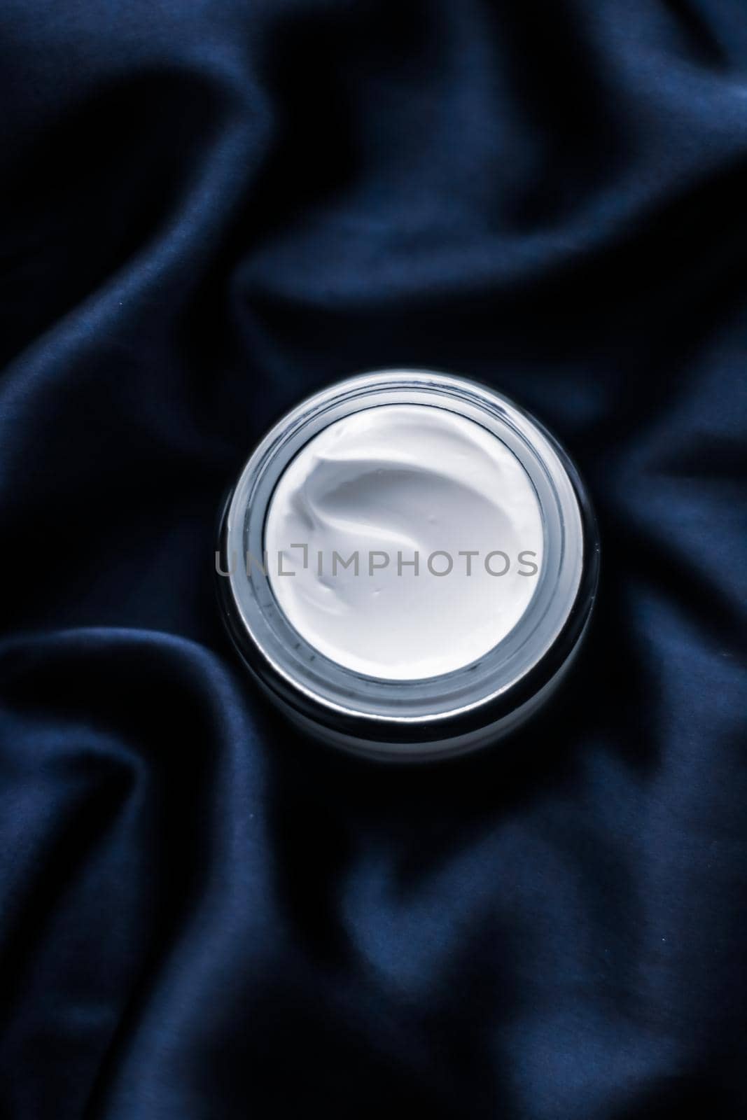 Beauty, anti-age cosmetics and skincare concept - Luxury face cream jar on a dark blue silk