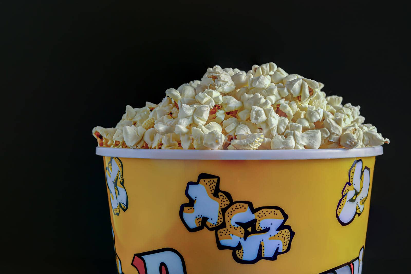 close-up of a popcorn container with colored letters on a black background