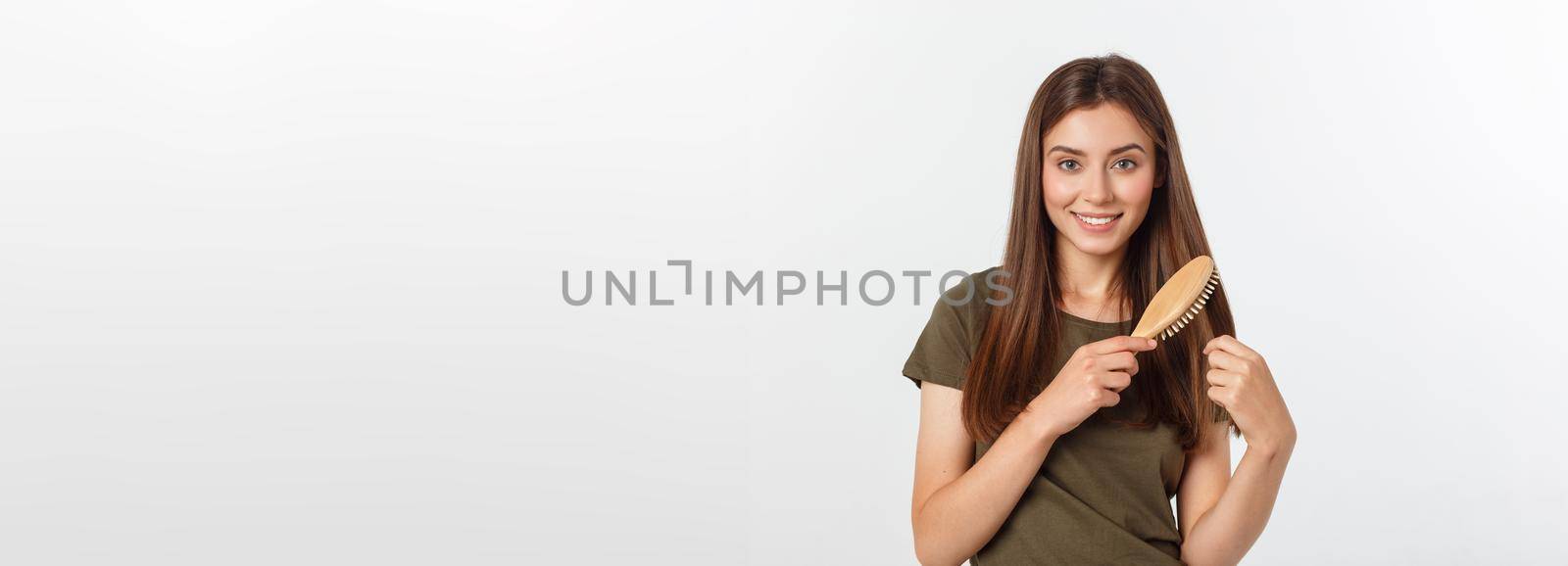 Happy young woman combing her long healthy hair on white background. by Benzoix